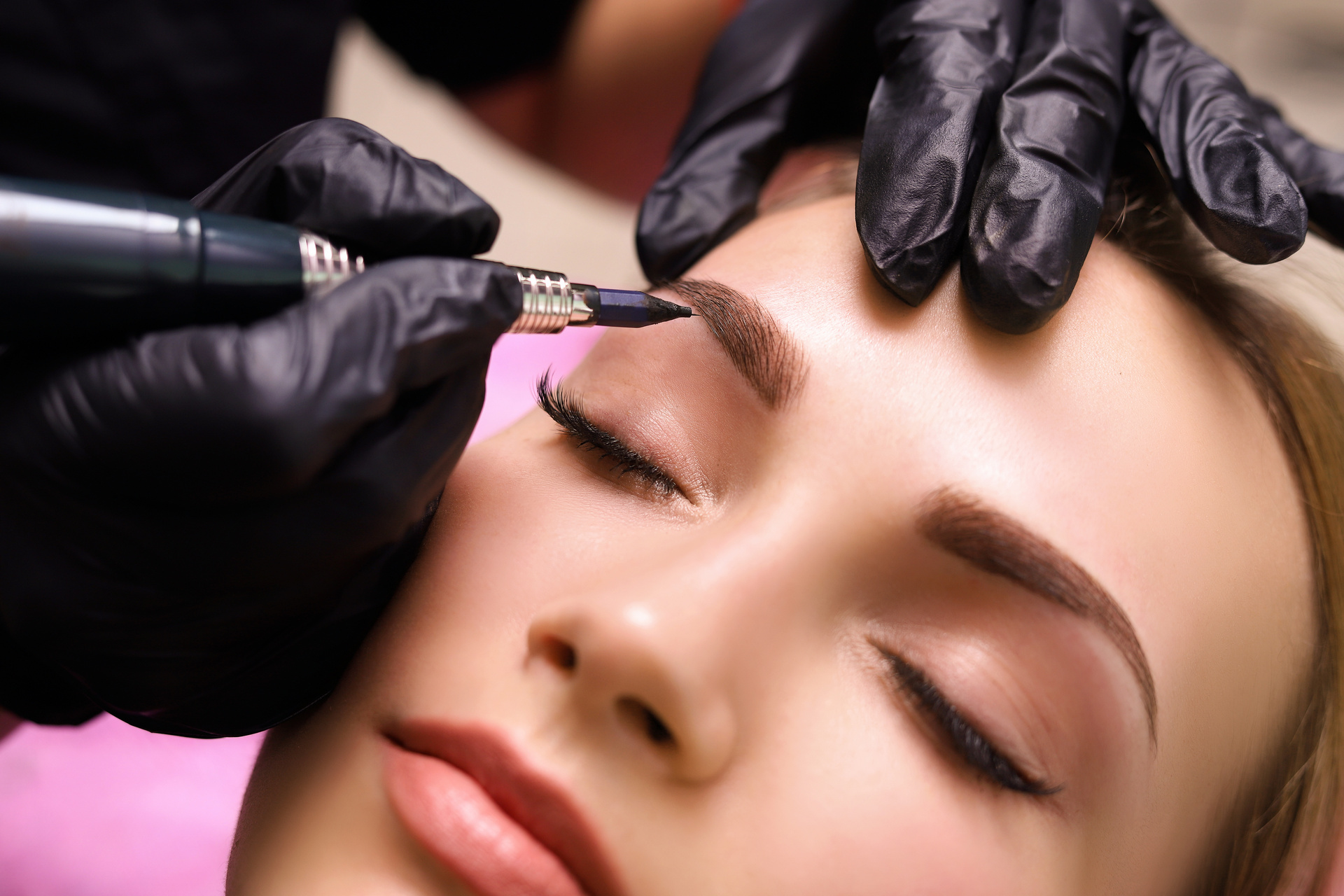 Cosmetologist applying permanent make up on eyebrows- eyebrow tattoo.